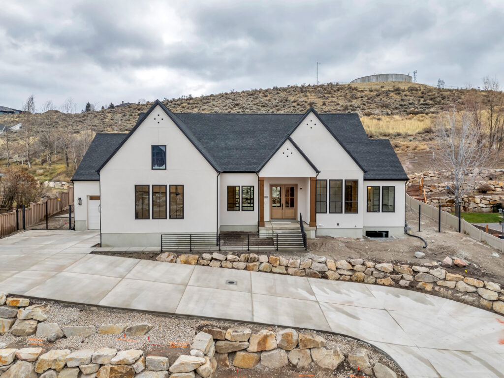 Modern English custom home exterior in Heber, Utah, with white stucco, black-framed windows, and natural wood entry columns