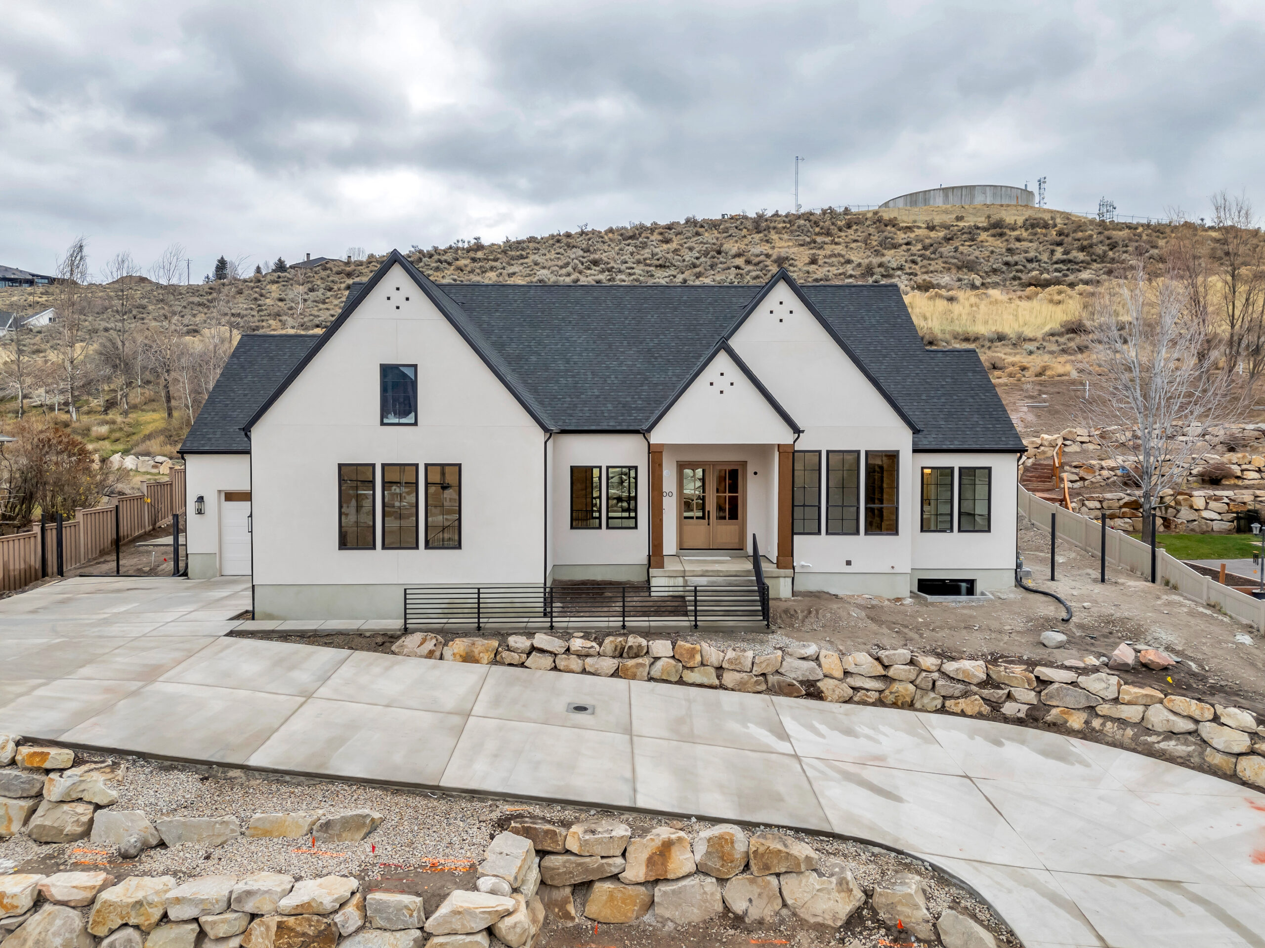 Modern English custom home exterior in Heber, Utah, with white stucco, black-framed windows, and natural wood entry columns
