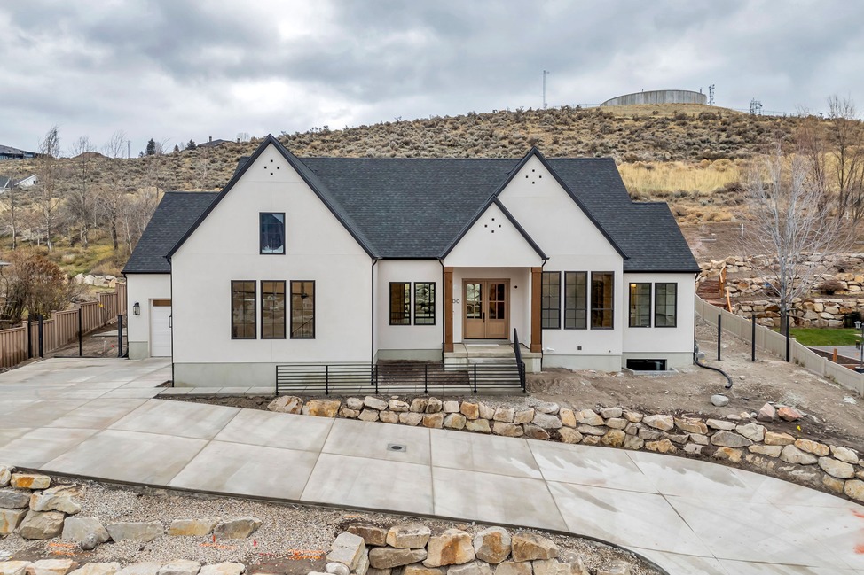 Heber Modern English — white modern English-style home with steep black gabled rooflines and hillside backdrop.