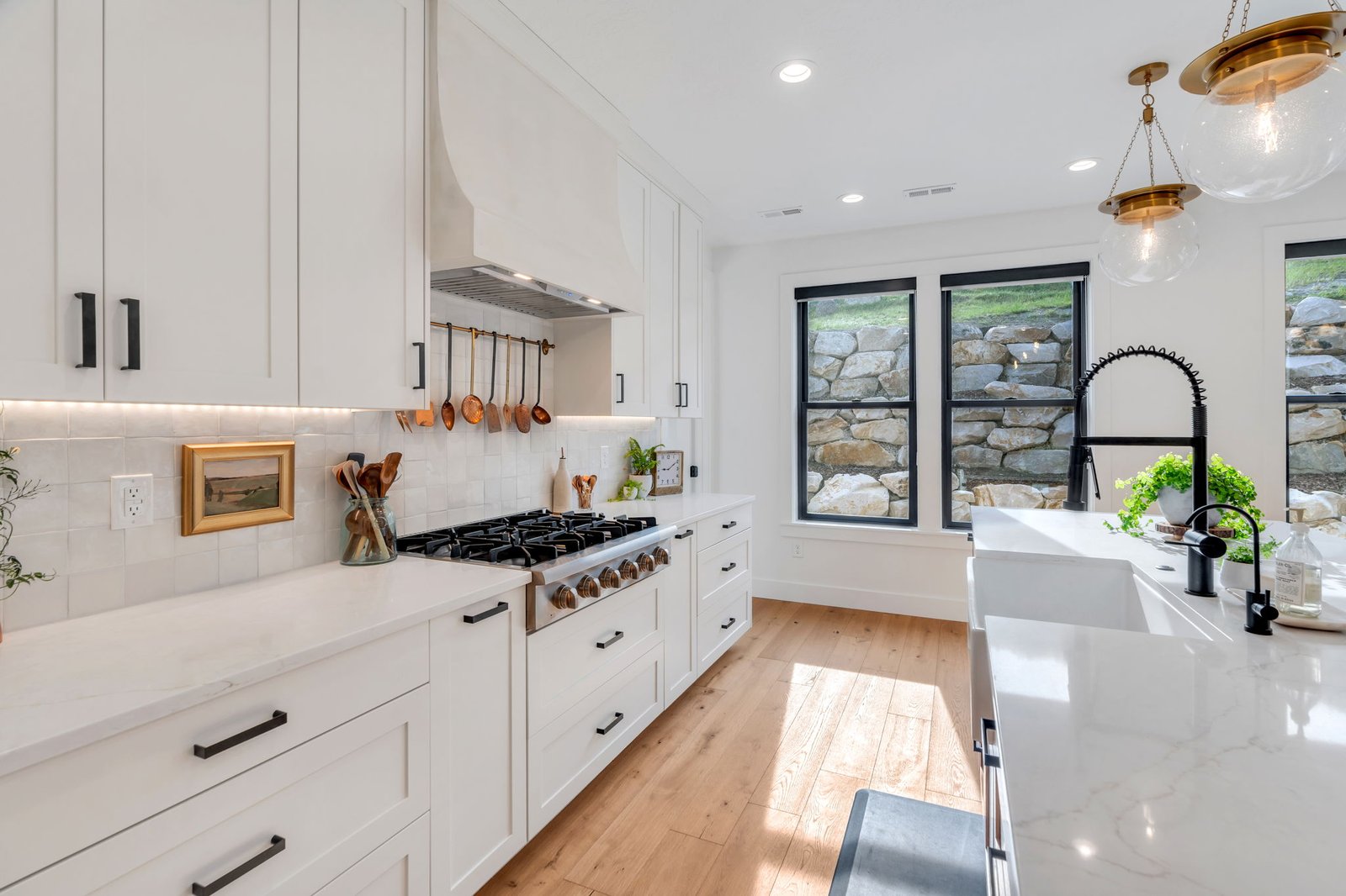 Custom white kitchen with quartz countertops and black hardware in a Utah County home by Haven Homes